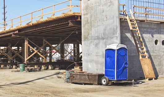 a clean and organized line of portable toilets at a job site, keeping workers content